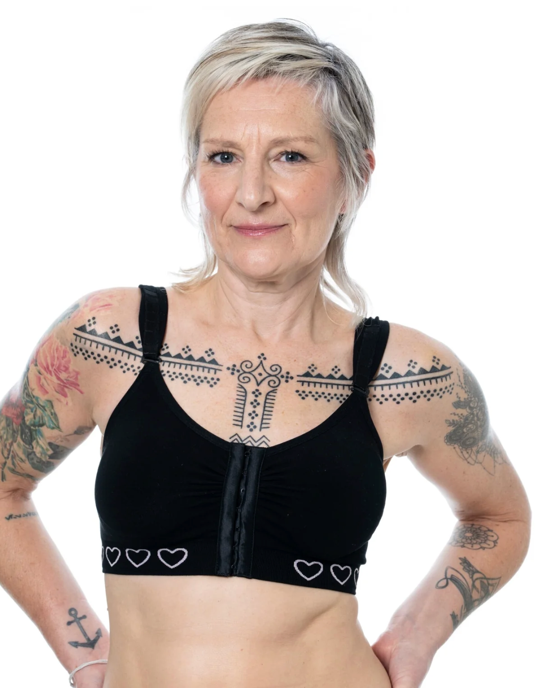Woman wearing a black post surgery bra with heart patterns on a white background