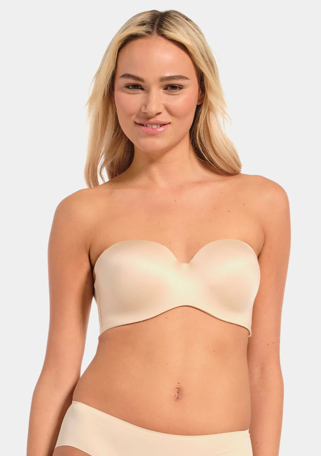 Woman wearing a beige strapless top against a plain background