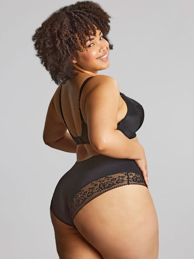 Woman wearing a black lingerie set with lace details on a gray background