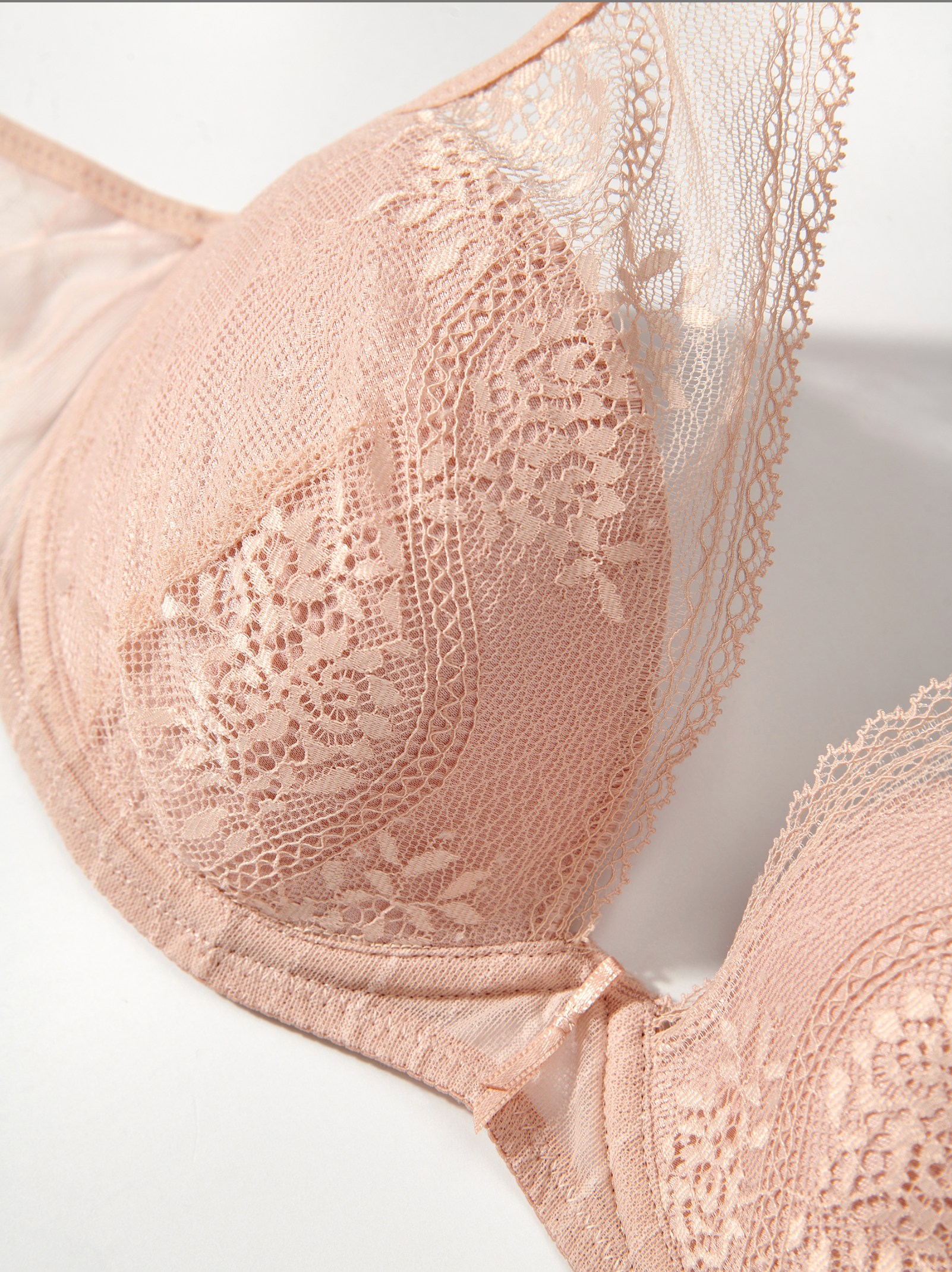 Close-up of a lace-trimmed pink bra on a white background