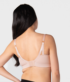 Woman wearing a ballet pink nursing bra against a light gray background