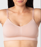 Woman wearing a ballet pink nursing bra against a neutral background