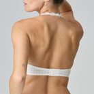 Woman wearing a white lace halter top and underwear set against a gray background