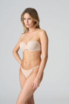 Woman wearing a beige strapless top and underwear set on a gray background