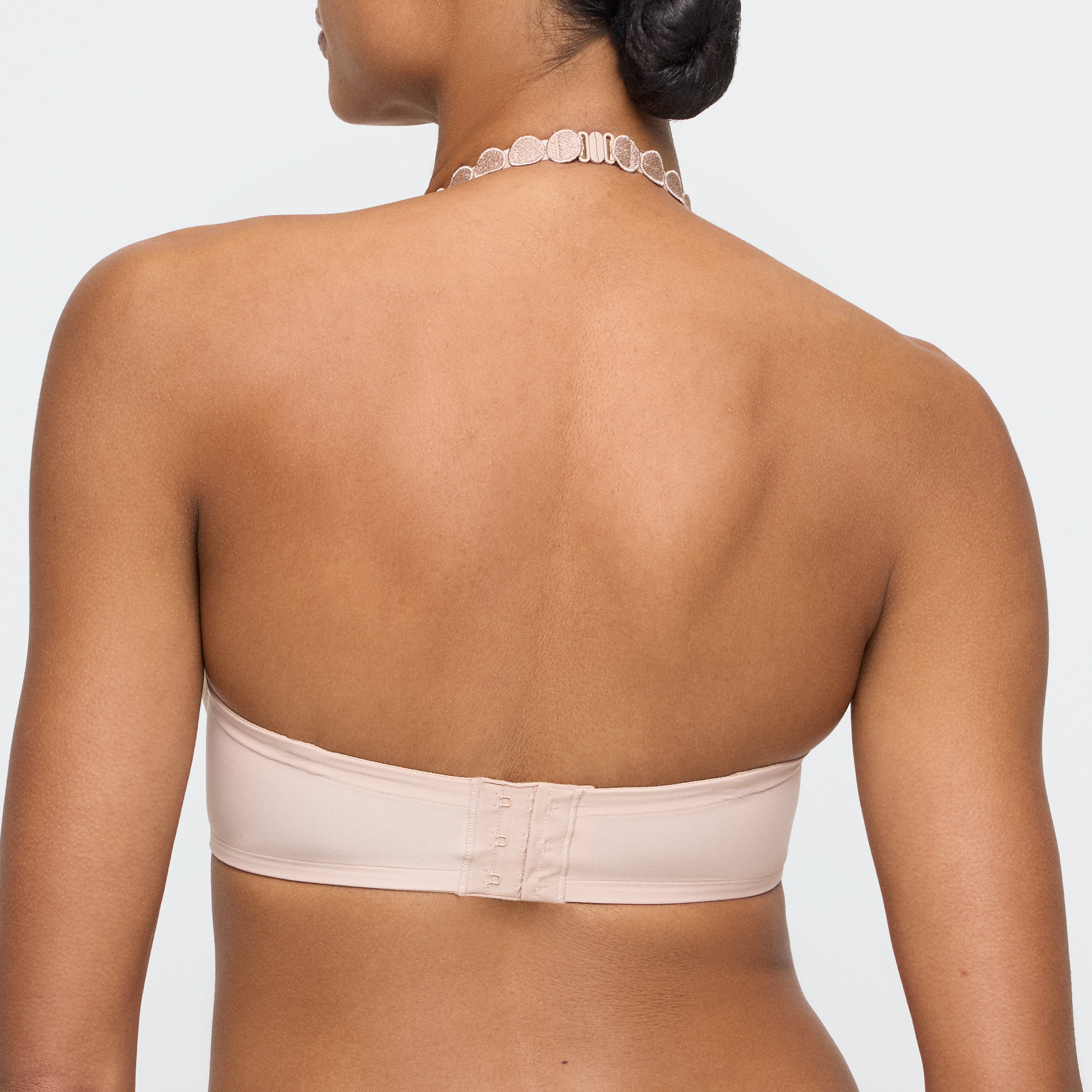 Woman wearing a beige strapless bra on a plain background