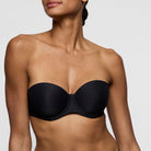 Black strapless bra worn by a model on a plain background