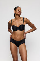 Woman wearing a black bra and panties set against a plain background