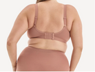 A woman shown from the back wearing a dusty rose/nude bra and matching underwear against a clean light gray studio background.