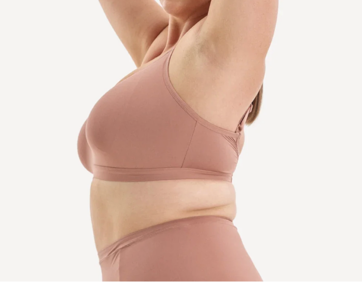 A close-up side view of a model wearing a dusty rose wireless bra and matching high-waisted bottoms against a clean white background.