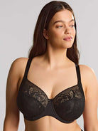 Woman wearing a black lace bra against a plain background