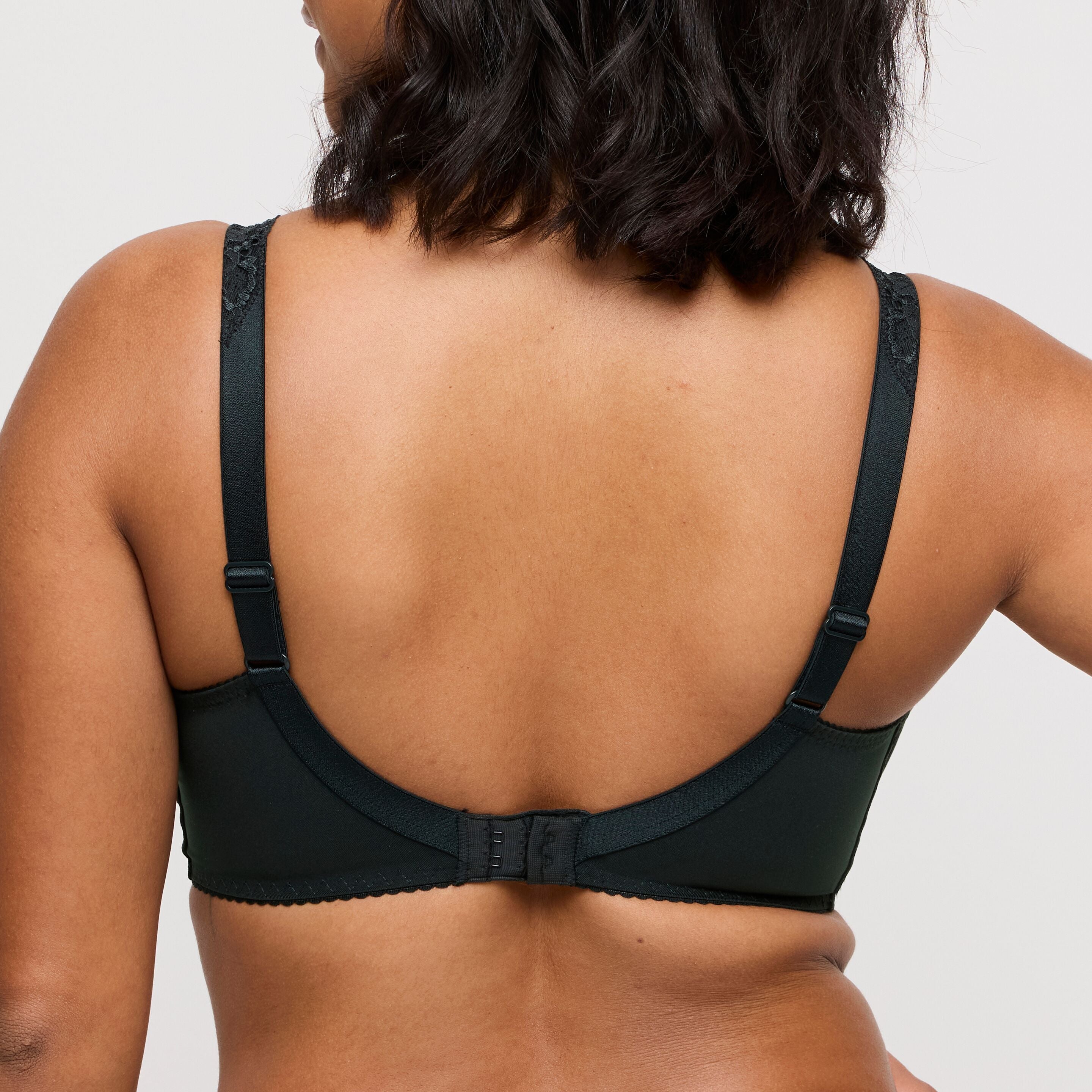Black bra worn by a person on a light gray background
