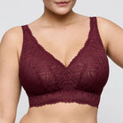 Maroon lace bralette worn by a person on a plain background