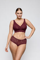 Woman wearing a burgundy lace lingerie set on a plain background