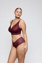 Woman wearing a burgundy lace lingerie set on a plain background