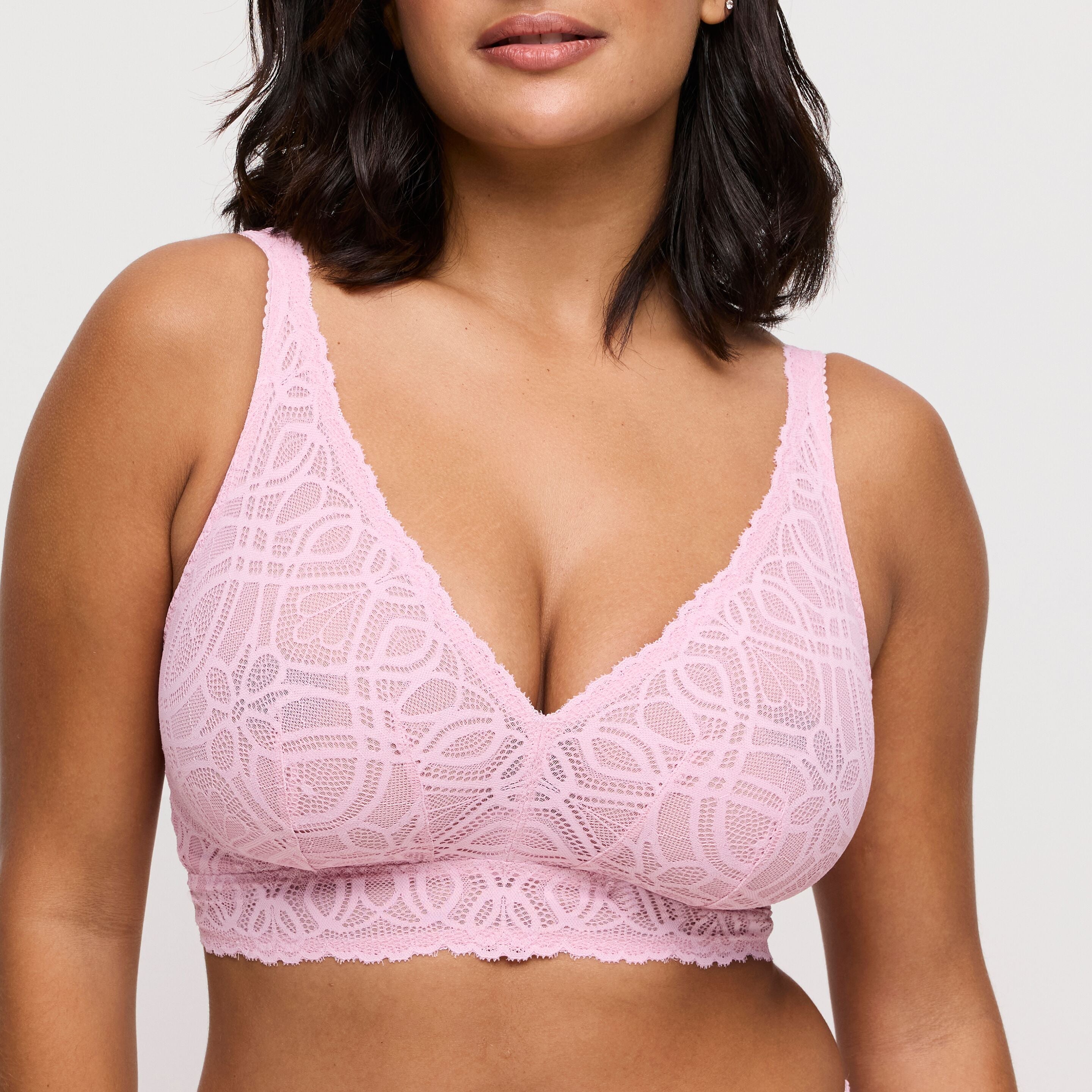Pink lace bra worn by a model on a plain background