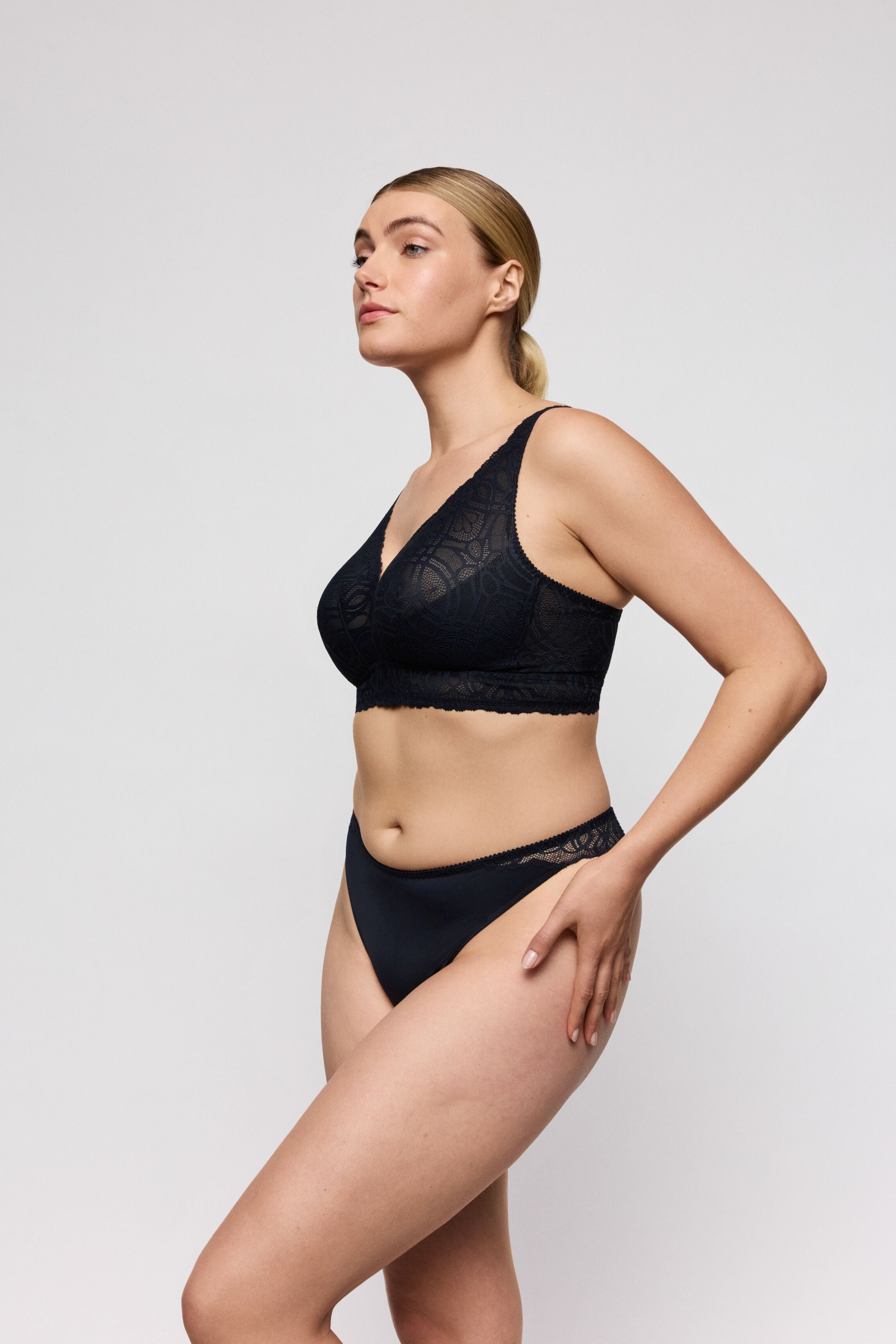 Woman wearing a midnight blue lace lingerie set on a plain background