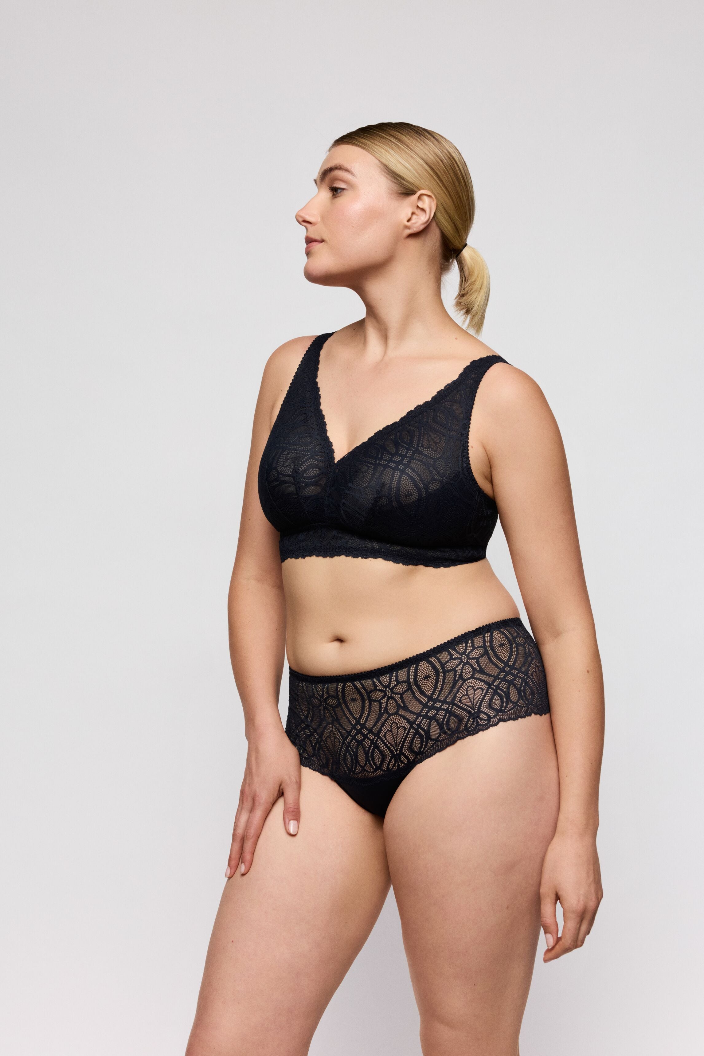 Woman wearing a wire free midnight blue bra and panties set on a plain background