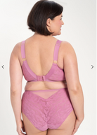 Woman wearing a pink bra and panties set on a white background