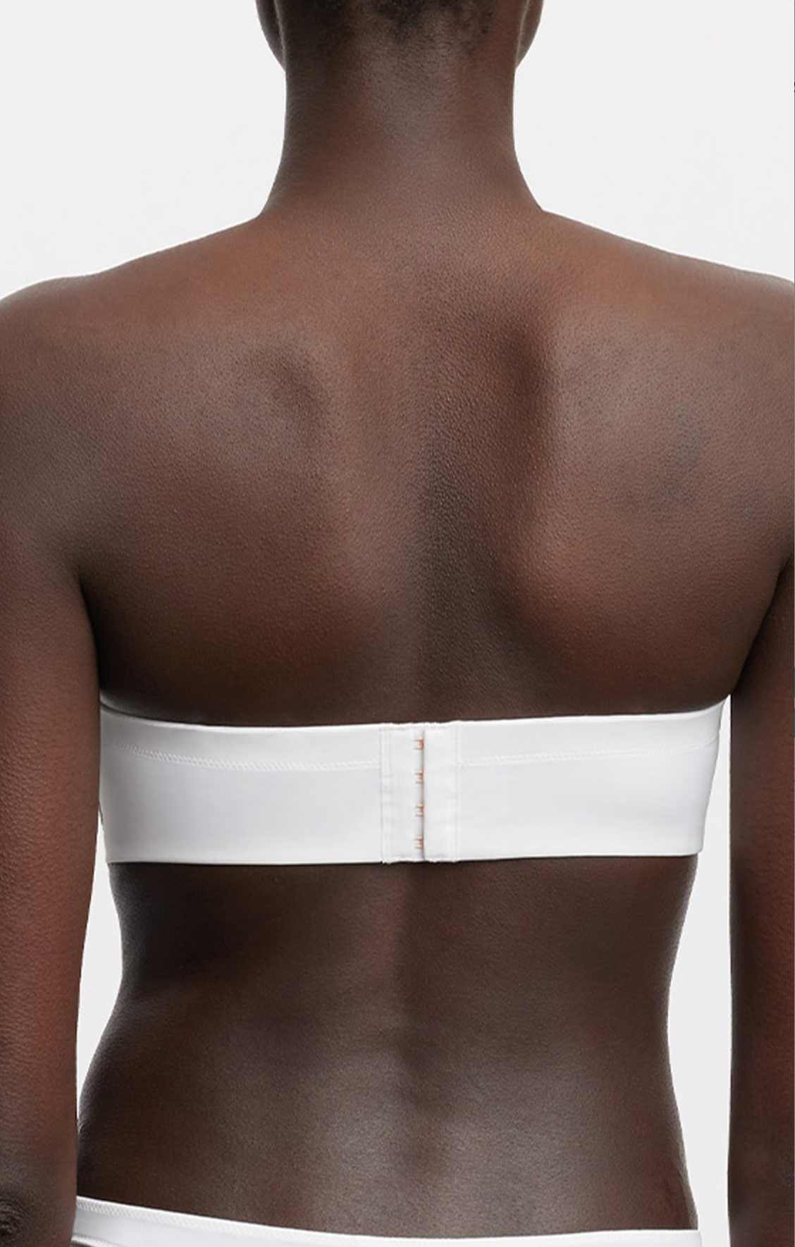 White strapless bra worn by a person on a plain background