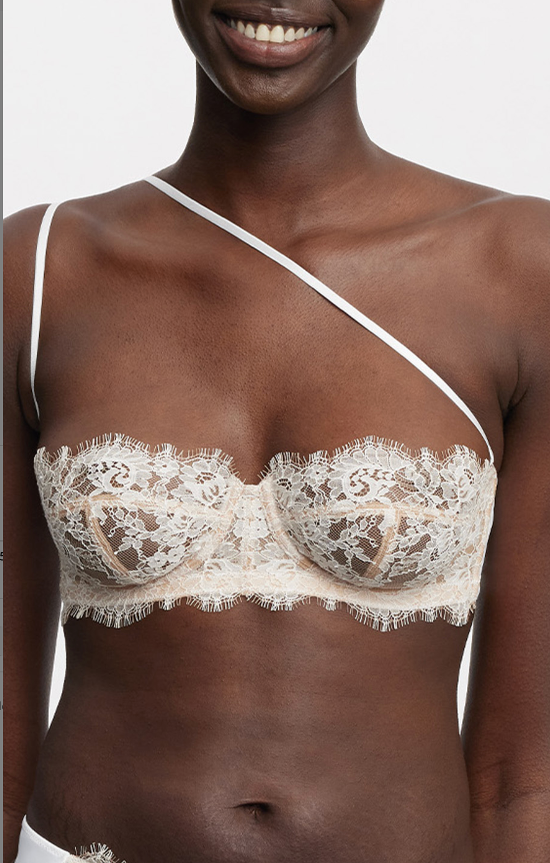 Woman wearing a beige lace bra against a white background