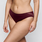 Maroon lace underwear worn by a person on a light gray background